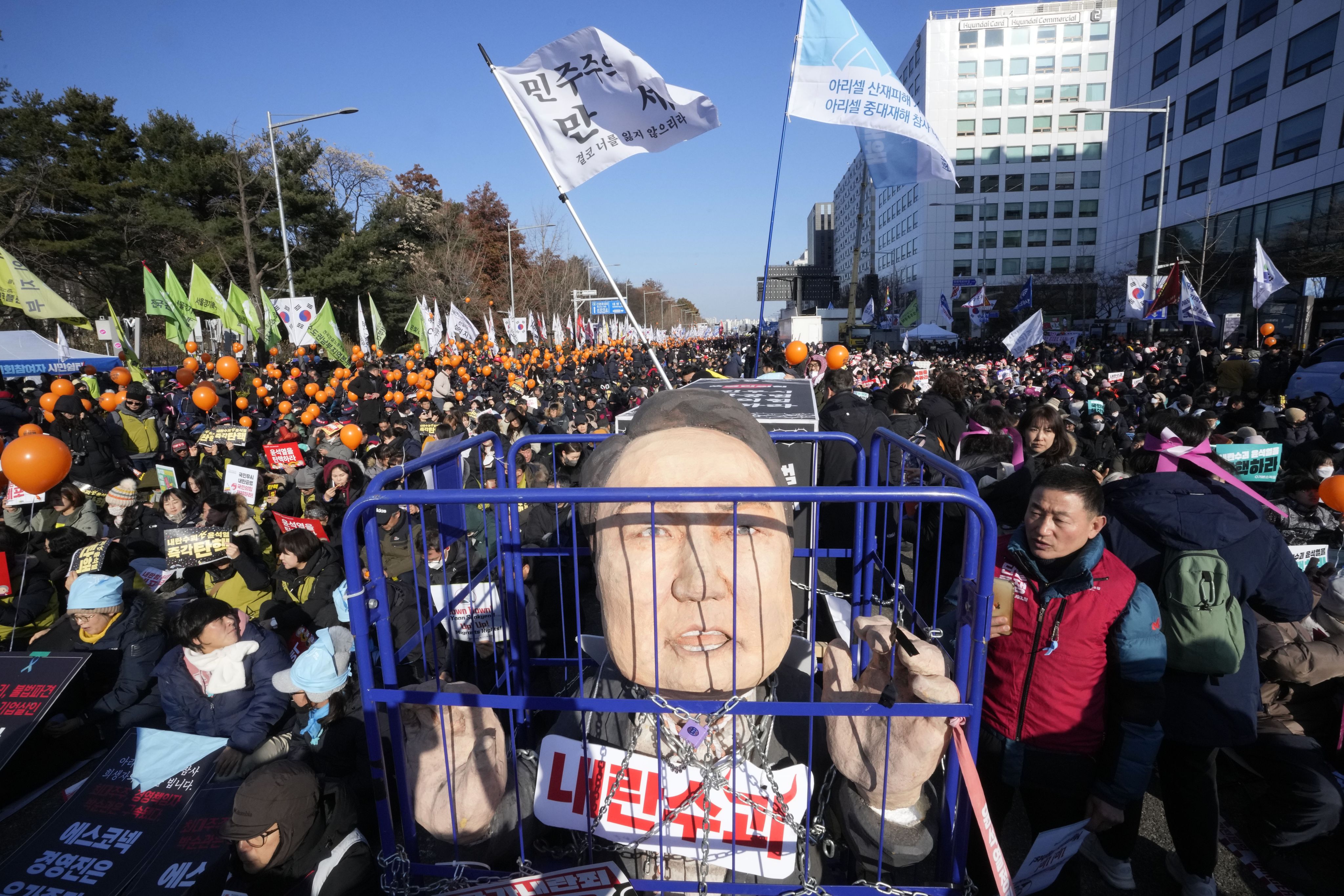 2024年12月14日，在韩国首尔国会外举行的要求弹劾韩国总统的集会上，示威者展示了被监禁的尹锡悦的形象。(AP Photo/Ahn Young-joon)