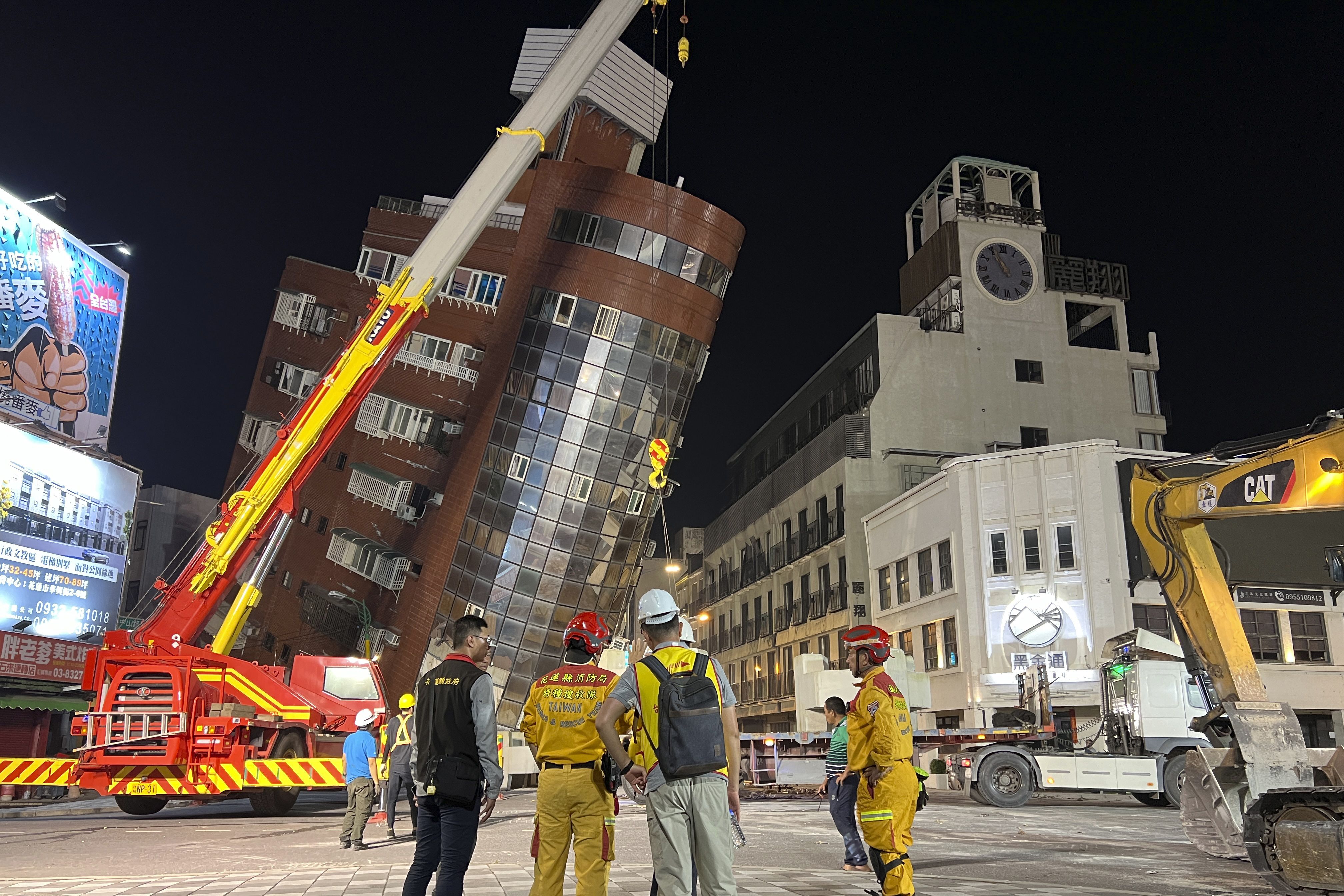 2024年4月3日，救援人员站在台湾东部花莲地震后一栋倾斜建筑物的现场附近。